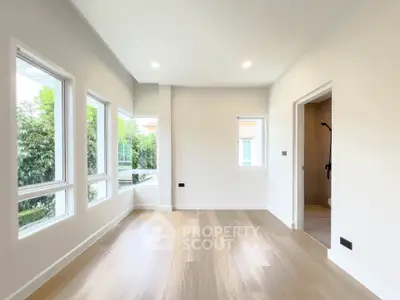 Spacious and bright room with large windows and wooden flooring, ideal for modern living.