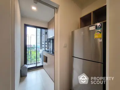 Modern kitchen with stainless steel fridge and balcony view in urban apartment