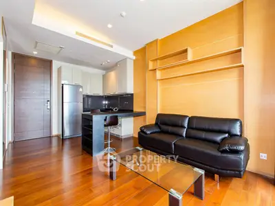 Modern living room with sleek black sofa and open kitchen layout in stylish apartment.