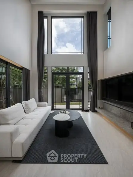 Luxurious modern living room with high ceilings and large windows offering a stunning view.