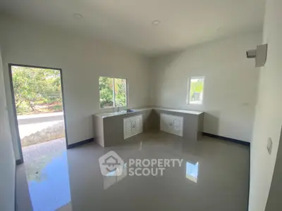 Spacious kitchen with modern design and ample natural light, featuring sleek countertops and large windows.