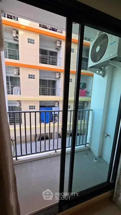 Compact balcony view with air conditioning unit in modern apartment complex.