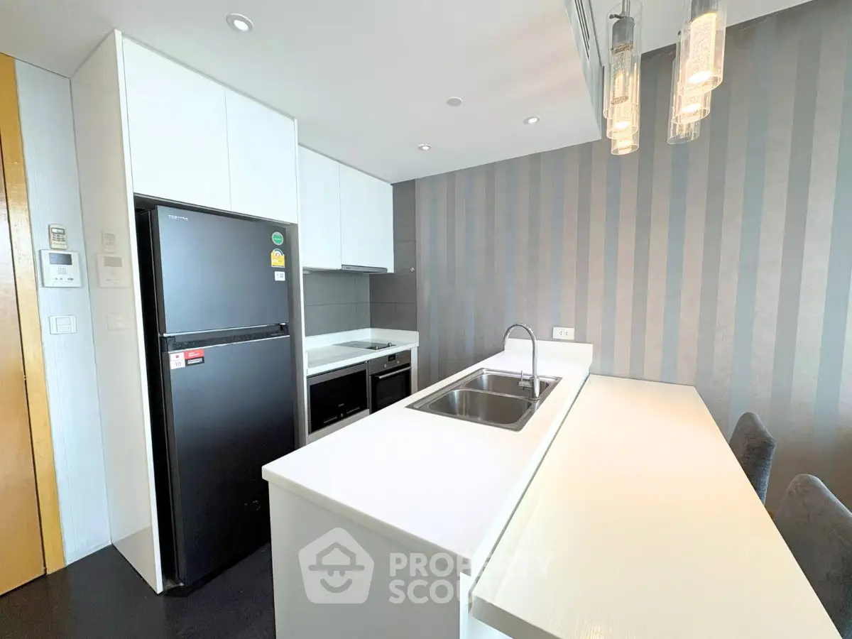Modern kitchen with sleek white cabinetry and black appliances in a stylish apartment.