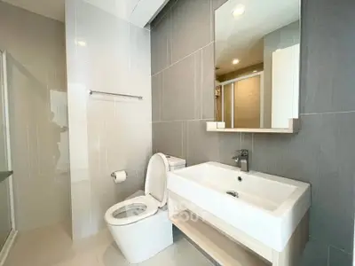Modern bathroom with sleek fixtures and neutral tiles, featuring a spacious shower and contemporary sink.
