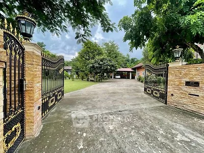 Stunning gated entrance to a luxurious estate with lush greenery and spacious driveway.