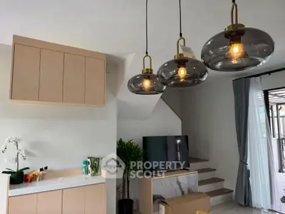 Modern living room with stylish lighting and staircase, featuring a sleek TV setup.