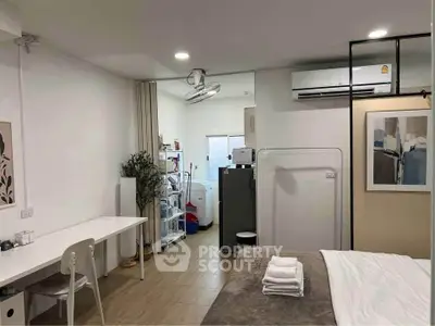 Modern studio apartment with stylish decor and efficient layout, featuring a cozy bed, workspace, and compact kitchen.