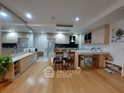 Spacious modern kitchen with open layout and dining area, featuring wooden flooring and sleek cabinetry.