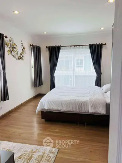 Spacious bedroom with elegant decor and large windows for natural light.