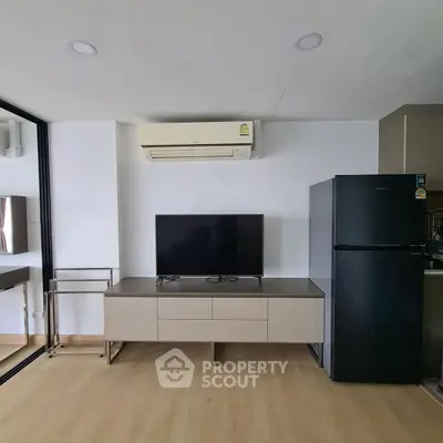 Modern living room with sleek TV stand, air conditioner, and black refrigerator.