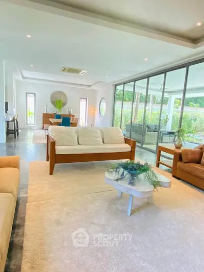 Spacious living room with modern decor and large windows overlooking garden