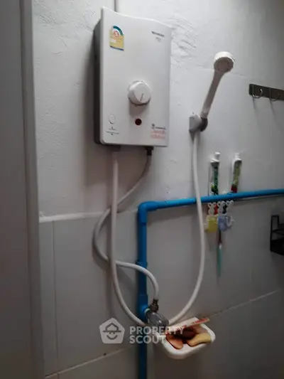 Compact bathroom with wall-mounted water heater and showerhead.