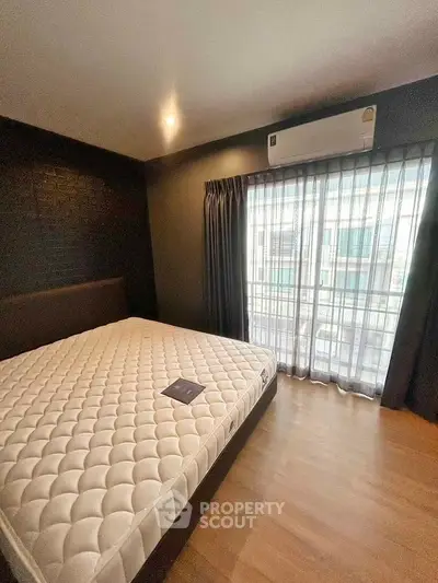 Modern bedroom with large window and air conditioning, featuring a comfortable bed and stylish decor.