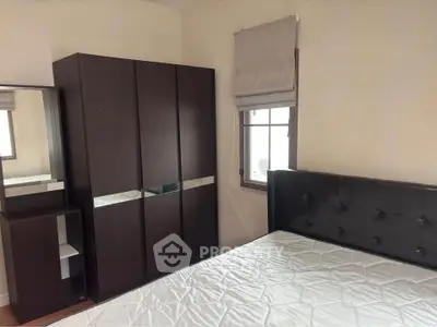 Cozy bedroom with modern wardrobe and large window for natural light.
