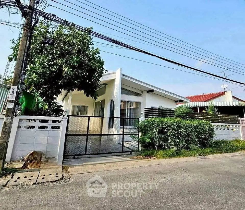 Charming single-story house with gated entrance and lush greenery in a serene neighborhood.