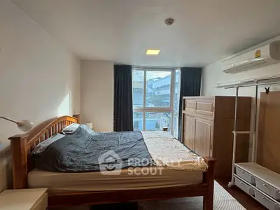 Cozy bedroom with wooden furniture and large window offering natural light.