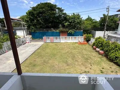 Spacious backyard view from balcony with lush greenery and clear blue sky.