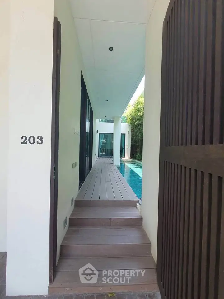 Modern villa entrance with poolside view and sleek architectural design