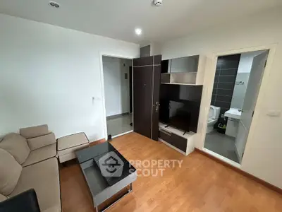 Modern living room with sleek furniture and wooden flooring, adjacent to a stylish bathroom.