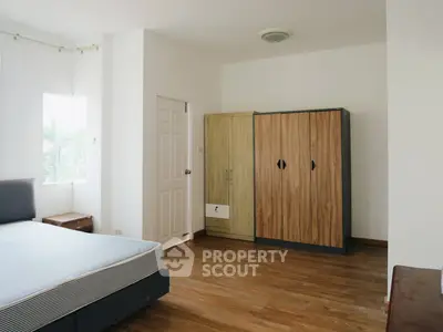 Spacious bedroom with wooden flooring and ample natural light