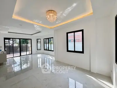 Spacious modern living room with large windows and elegant chandelier