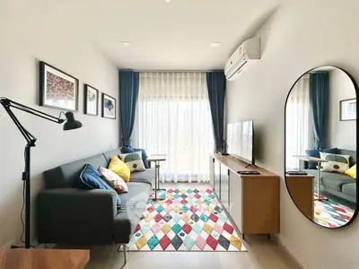 Modern living room with colorful rug and large window, featuring stylish decor and ample natural light.