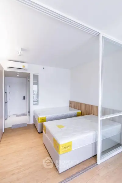 Modern bedroom with twin beds and sliding glass partition in bright apartment