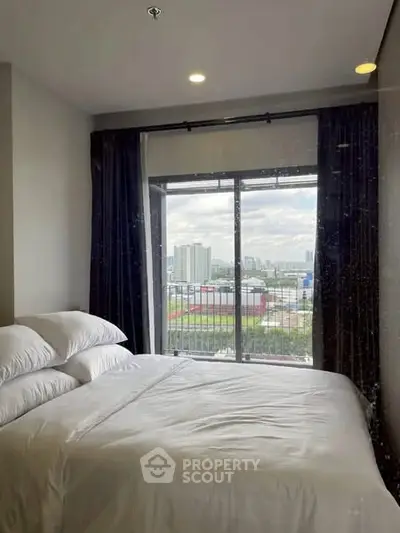 Cozy bedroom with city view and large window for natural light.