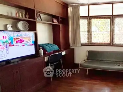 Cozy living room with wooden flooring, TV, and large window for natural light.