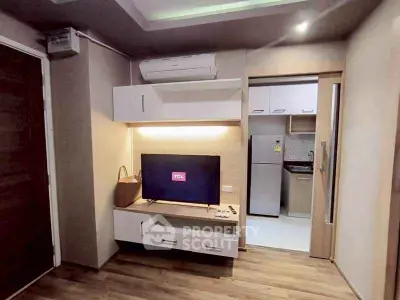 Modern living room with TV and kitchen view, featuring sleek design and wooden flooring.