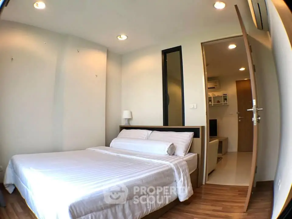 Cozy bedroom with wooden flooring and modern lighting in a stylish apartment.