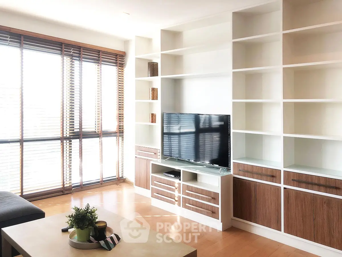 Spacious living room with modern built-in shelves and large windows for natural light.