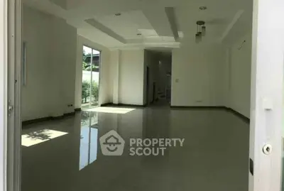 Spacious empty room with glossy floors and large windows in modern home.