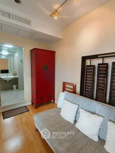 Cozy living room with stylish furniture and wooden flooring, adjacent to a modern bathroom.
