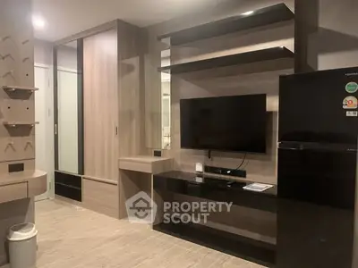 Modern living room with sleek TV unit and refrigerator, showcasing contemporary design and ample storage.