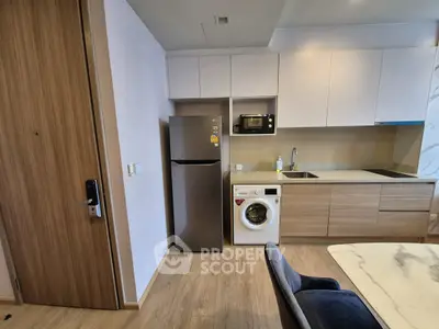 Modern kitchen with sleek appliances and washer, featuring wooden cabinetry and marble dining table.