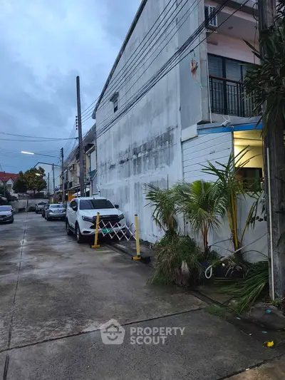 Urban residential street with parked cars and modern townhouses, showcasing potential investment opportunity.