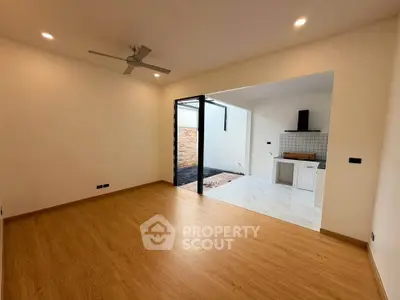 Spacious open-plan living room with wooden flooring and modern kitchen area.