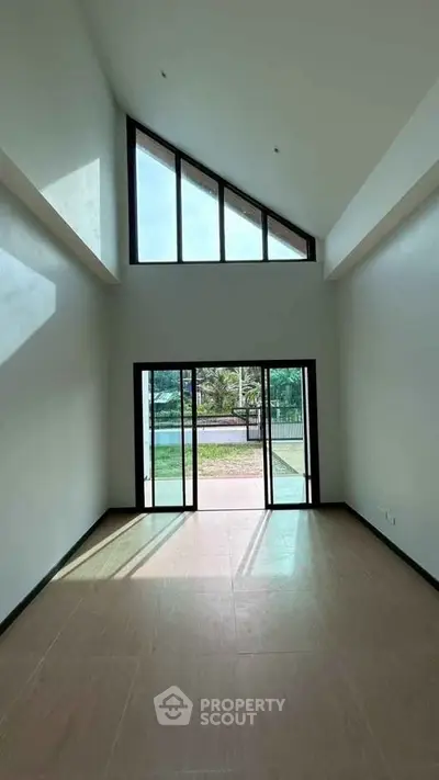 Spacious room with high ceilings and large windows offering garden view