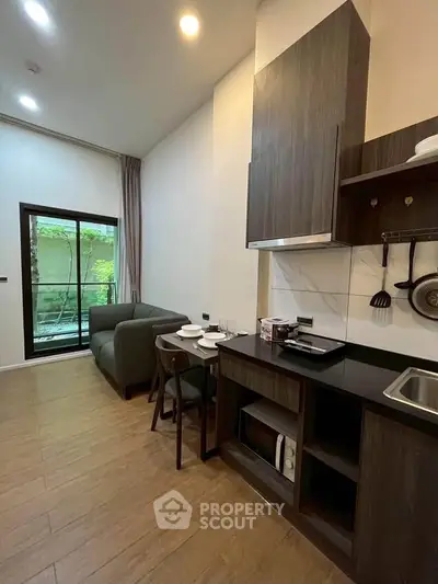 Modern living room with open kitchen and garden view, featuring sleek wooden flooring and contemporary furniture.