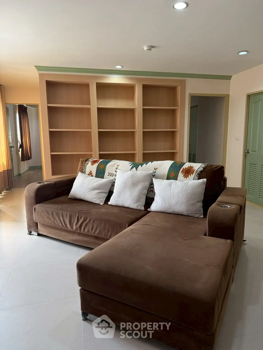 Spacious living room with brown sectional sofa and built-in wooden shelves