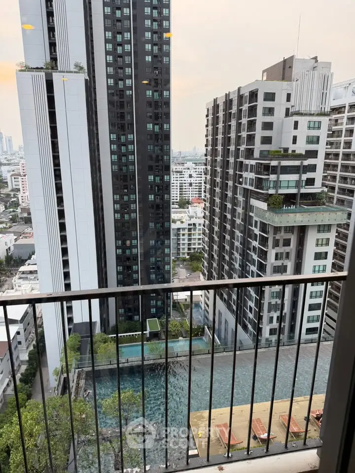 Stunning cityscape view from a high-rise balcony overlooking modern skyscrapers and a luxurious pool.