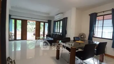 Spacious living room with modern furniture and large windows opening to a garden view.