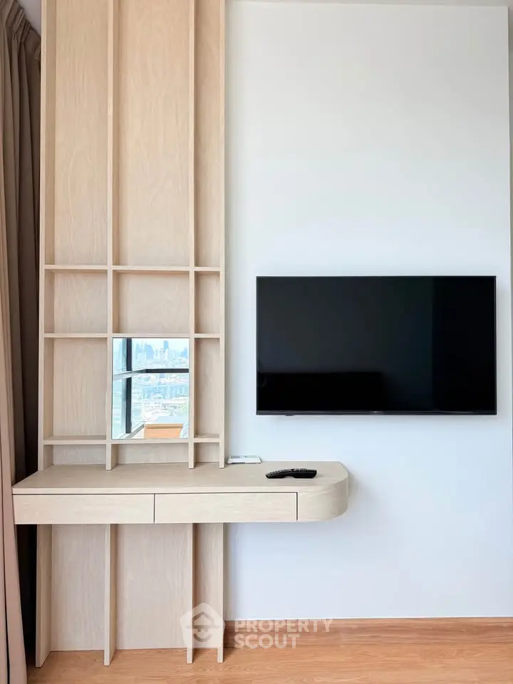 Modern living room with sleek TV setup and stylish wooden shelving unit.