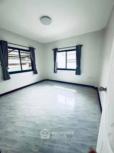 Spacious empty bedroom with large windows and tiled flooring, perfect for customization.