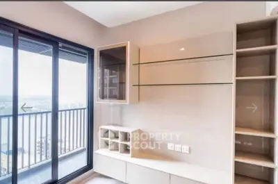 Modern living room with built-in shelves and balcony view in high-rise apartment.