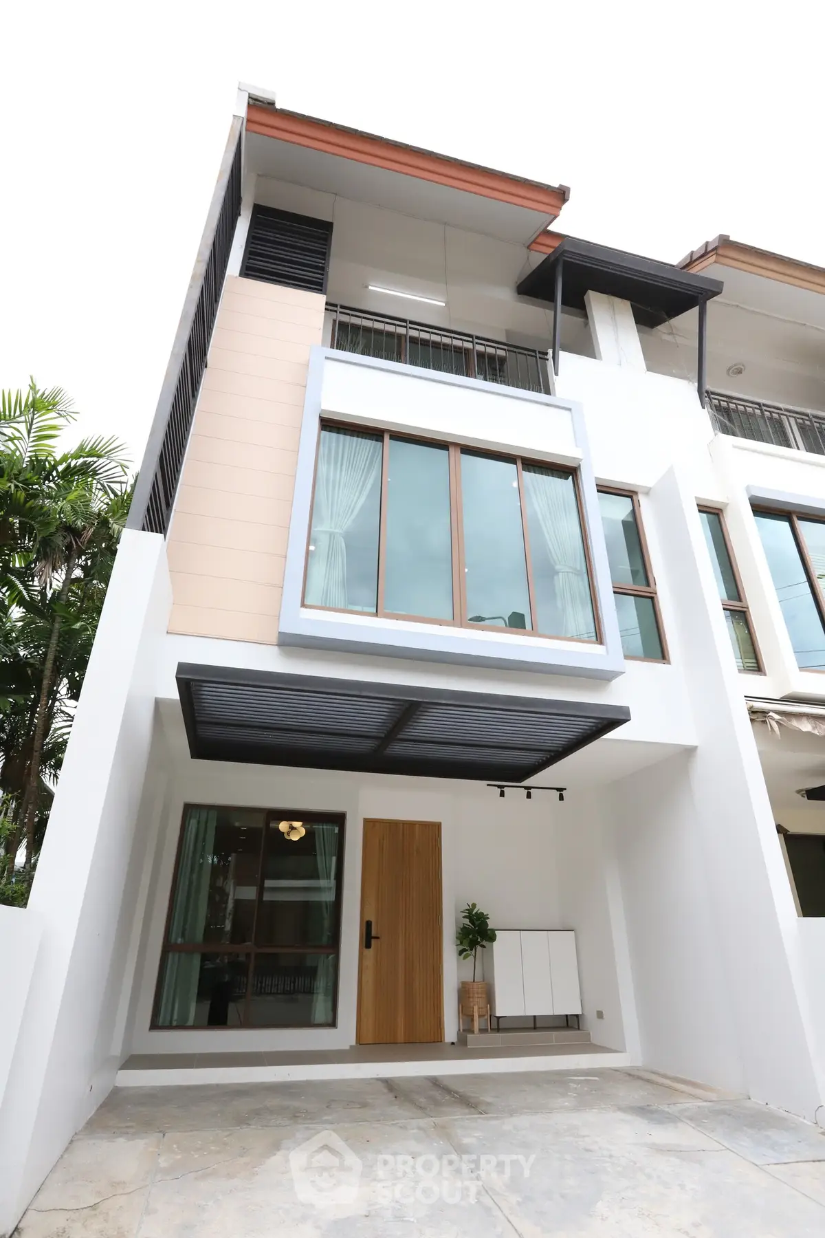 Modern townhouse exterior with large windows and stylish entrance in a serene neighborhood.