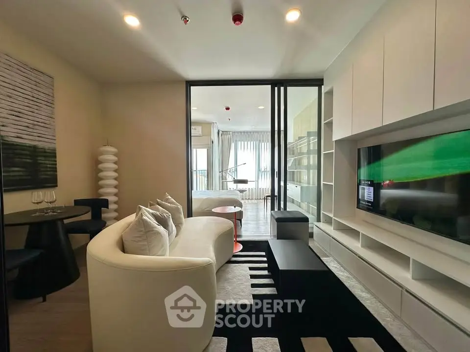 Modern living room with sleek furniture and large TV, featuring a stylish open layout and elegant decor.