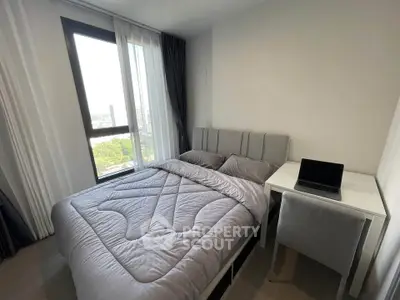 Modern bedroom with large window and cozy bedding, featuring a sleek desk and chair setup.