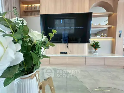Modern living room with large TV, elegant decor, and stylish shelving.